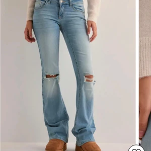 Ljusblå bootcut jeans - Blåa bootcut jeans med hål och fickor, använda ett fåtal gånger så är i bra skick