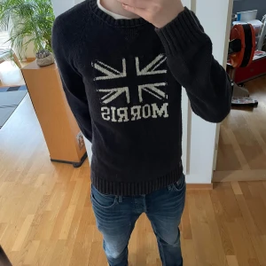 Morris Stickad Tröja - Säljer en sjukt fet unik svart stickad tröja från Morris. Tröjan har Storbritanniens flagg på sig och är gjord i ett tjockt material. Den är i bra men använt skick och i storlek S men kan även passa strl M. Hör gärna av er vid frågor eller funderingar!!