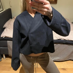 Marinblå omlott tröja från Gina Tricot - Snygg marinblå omlott tröja från Gina Tricot i storlek M. Tröjan har en stilren design med långa ärmar och en v-ringad hals. Perfekt för en trendig look.