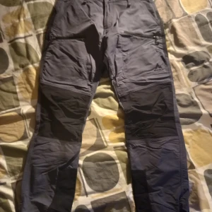 Blå/Grå cargopants McKinley - Snygga grå cargopants med flera praktiska fickor. Byxorna har en loose passform och är perfekta för en avslappnad stil. Tillverkade i slitstarkt material som passar bra för utomhusaktiviteter.