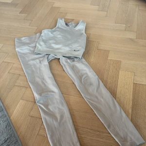 Grått set med linne och leggings från stronger - Snyggt och bekvämt grått set från Stronger bestående av ett ribbat linne och matchande leggings. Perfekt för träning eller en avslappnad dag. Linnet har en enkel design och leggingsen är stretchiga för bästa passform.