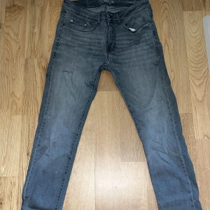 Grå jeans från Dressmann - Snygga grå jeans från Dressmann i slim fit. De har en klassisk femficksdesign och en dragkedja framtill. Perfekta för en stilren look.