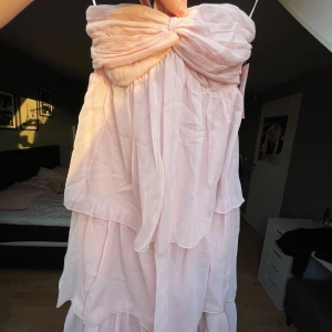 Ljusrosa klänning från Nelly - Säljer en drömmig ljusrosa klänning från Nelly med volangdetaljer. Klänningen är axelbandslös och har en smockad överdel för en bekväm passform. Perfekt för sommarens festligheter! Skulle säga att den passar xxs-s
