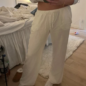 Vita linnebyxor från Madlady - Snygga vita linnebyxor från Madlady med en avslappnad passform. Byxorna har en elastisk midja för extra komfort och är perfekta för en stilren look. De är tillverkade i ett lätt och luftigt material, vilket gör dem idealiska för varmare dagar.