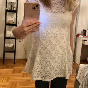 Vit spets klänning - Säljer en söt vit spets klänning med ärmlös design.  Klänningen har en lätt utsvängd passform och är perfekt för en romantisk look. Den är tillverkad i ett vackert spetsmaterial som ger en elegant känsla.