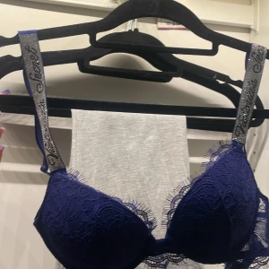 Blå spets-bh från Victoria's Secret - Säljer en snygg blå push-up bh från Victoria's Secret med spetsdetaljer och glittriga axelband. Bh:n är i storlek 34A/75A och har en bekväm passform.Köpt här på plick för 800 men säljer vidare då den inte används, har används 1 gång.Kan diskutera pris.