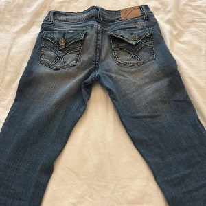 Blå jeans med slitna detaljer - Snygga blå jeans från Vanity med slitna detaljer och dekorativa sömmar på bakfickorna. Bootcut byxor, dem har ingen specifik men passar mig som oftast har storlek 34-36 men andra mått kan jag skicka  om du är intresserad 💕