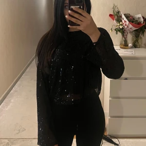 Svart glittrig tröja - Säljer en svart glittrig tröja med långa ärmar. Perfekt för en kväll ute eller en festlig tillställning. Tröjan har en lös passform och är både bekväm och stilren. Passar bra till både jeans och kjol. ✨