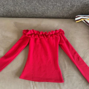 Röd offshoulder topp från Only Trend - Säljer en snygg röd offshoulder topp från Only Trend i storlek XS. Toppen har långa ärmar och en volangdetalj runt halsringningen. Perfekt för att ge en färgklick till din outfit!