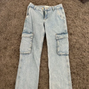 Ljusa cargobyxor från grina tricot - Snygga ljusa cargobyxor i jeansmaterial. Byxorna har flera praktiska fickor och en avslappnad passform. Perfekta för en casual look.