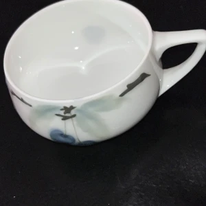 Vit kopp med blått mönster från Rosenthal - Elegant vit kopp från Rosenthal med ett subtilt blått mönster av bär och fåglar. Koppen har ett bekvämt handtag och är märkt med 'Donatello' och 'Bavaria' på undersidan. Perfekt för en stilfull fika eller som samlarobjekt.