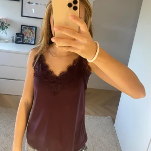 Lila linnetopp från Amisu - Säljer en snygg lila linnetopp från Amisu i storlek XS. Toppen har spetsdetaljer vid halsringningen och tunna axelband. Perfekt för en stilren look😘