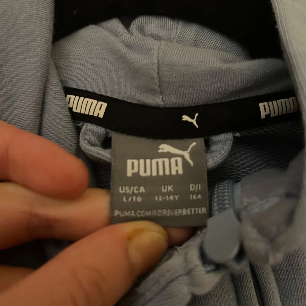 Säljer en stilren blå hoodie från Puma med dragkedja och huva. Tröjan har långa ärmar och en praktisk ficka framtill. Perfekt för en avslappnad look.. Neuletakit & Villapaidat.