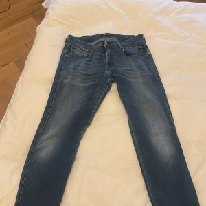 Blå jeans från Replay - Snygga blå jeans från Replay med en klassisk femficksdesign och dragkedja. Jeansen har en normal passform och är perfekta för en avslappnad stil. Märket Replay är synligt på insidan av midjan.