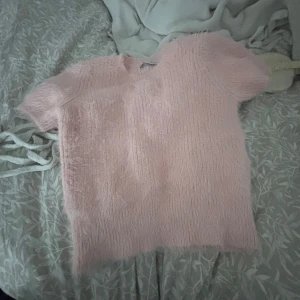 Rosa fluffig tröja - Säljer en supermjuk och fluffig rosa tröja med korta ärmar. Perfekt för en mysig och stilren look. Tröjan har en enkel design som gör den lätt att matcha med olika outfits. Passar perfekt för vår och sommar. Storlek m men sitter som en s. 