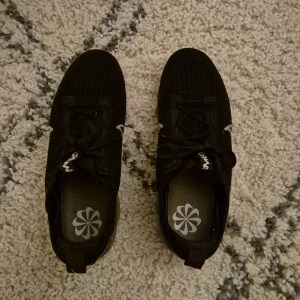 Svarta Nike Vapormax sneakers. Storlek 41 - Säljer ett par svarta Nike Vapormax sneakers med vit swoosh och transparent sula. Skorna har snörning och en modern design som passar perfekt för träning eller en avslappnad stil. Storlek 41 