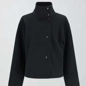 Mörkblå kappa med hög krage - Snygg mörkblå jacka med hög krage och knäppning framtill. Jackan har långa ärmar och en stilren design som passar perfekt för kyligare dagar. Perfekt för dig som gillar en minimalistisk stil. Modellen short felt från Gina och är mer blå i verkligheten än på första bilden!!❤️