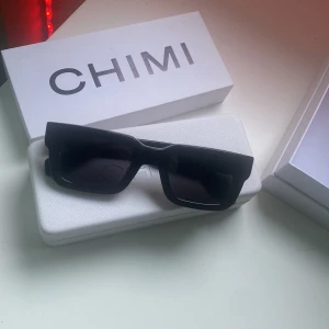 Svarta solglasögon från CHIMI - Snygga svarta solglasögon från CHIMI med en modern, rektangulär form. Designade i Stockholm och kommer med ett stilrent vitt fodral. Perfekta för att ge en cool touch till din outfit.