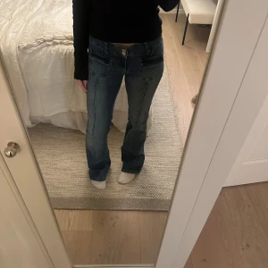 Blå jeans från Nelly - Jättefina blå bootcut jeans från Nelly! De är låga i midjan och har dubbla knappar. Köpta i höstas för ca 700kr och använda ett fåtal gånger! Storlek 34💗