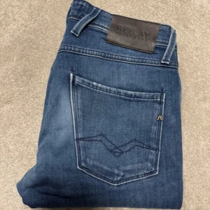 Blå jeans från Replay - Snygga blå jeans från Replay med klassisk femficksdesign och en diskret logga på bakfickan. Jeansen har en knappgylf och är perfekta för en avslappnad stil. De har en modern passform som är både bekväm och stilren. W31/L32