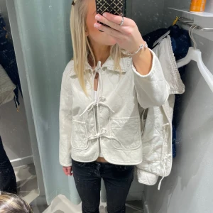 Jacka  - Säljer en stilren vit quiltad jacka från Vera Moda med prislapp på. Jackan har knytband framtill och stora fickor. Den har en klassisk krage och långa ärmar, perfekt för en trendig look. Passar bra till både jeans och kjol. Storlek L men passar påse för S oxh M storlekar💕💕