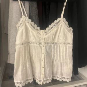 Vit spetslinne med knappar - Charmigt vitt linne med spetsdetaljer och knappar framtill. Tunna axelband och vacker spetskant ger en romantisk känsla. Perfekt för varma dagar eller som ett lager under en kofta. 💗 Jättesöt och från zara men slutsåld 💔 Perfekt nu till våren