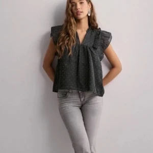 Svart blus med glitter från Neo Noir - Aldrig använd! Snygg svart blus från Neo Noir med silver prickar och volangdetaljer vid ärmarna. Pris kan diskuteras 