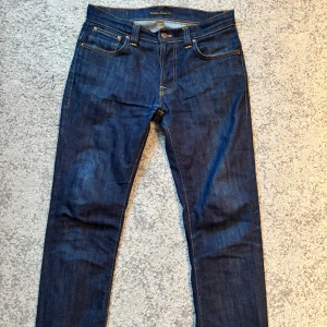 Mörkblå jeansbyxor från Nudie Jeans - Snygga mörkblå jeansbyxor från Nudie Jeans i storlek 31/32, passar perfekt även om du har en storlek mindre. Hör av dig om du är intresserad!!