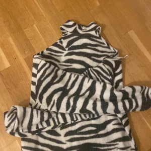 Zebramönstrad tröja från Gina Tricot - Säljer en cool zebramönstrad tröja från Gina Tricot. Tröjan har en hög krage och långa ärmar, perfekt för att sticka ut i mängden. Den är i en mjuk och bekväm kvalitet som passar bra till både jeans och kjol. 🦓✨ 