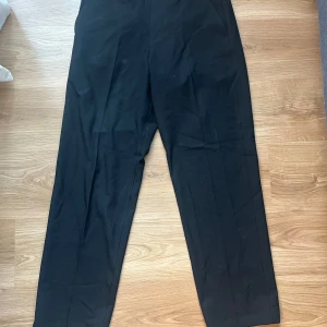 Svarta kostymbyxor från Selected Homme - Snygga svarta kostymbyxor från Selected Homme. De har en klassisk design med en rak passform och midwaist. Perfekta för en stilren look. Tillverkade i ett bekvämt material som ger en elegant känsla.