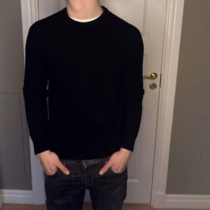 Svart tröja i merinoull från Vailent - Säljer en stilren svart tröja från Vailent i mjuk merinoull. Perfekt för kyligare dagar med sin klassiska design och bekväma passform. Tröjan har långa ärmar och rund halsringning. Passar XS där av priset.
