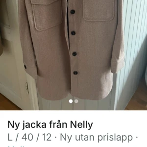 Beige jacka från Nelly - Snygg beige jacka från Nelly med stora knappar och praktiska fickor framtill. Jackan har långa ärmar och en stilren design som passar perfekt för höst och vår. Perfekt för att hålla stilen när det blir lite kyligare ute.
