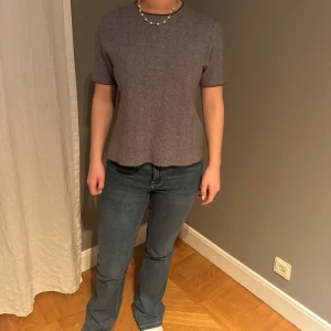 Grå kortärmad topp - Säljer en stilren grå topp med korta ärmar. Perfekt för en avslappnad look. Toppen har en enkel design och är lätt att matcha med olika outfits.