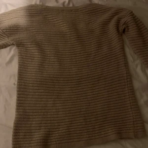 Beige ribbad tröja - Säljer en stilren beige tröja med ribbad struktur. Tröjan har långa ärmar och en klassisk passform som passar perfekt för kyligare dagar. Perfekt för dig som gillar en enkel och tidlös stil.