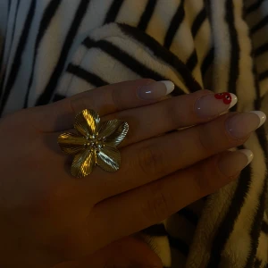 Guldfärgad blomformad ring - Säljer en vacker guldfärgad ring formad som en blomma. Perfekt för att ge en extra touch till din outfit. Aldrig använd, justerbar storlek 💓