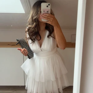 Studentklänning  - Säljer en superfin vit kort student klänning med volangdetaljer och v-ringad. Klänningen har en omlott-look och ger en luftig känsla. Från Gina Tricot i storlek Xs