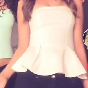 Vit  topp - Snygg vit axelbandslös topp med volangdetalj i nederkant. Perfekt för en stilren och chic look. Passar bra till både jeans och kjol.