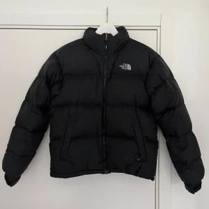 The North Face Dunjacka - 1996 Retro Nuptse Jacket - Original jacka köpt för många många år sedan. Knappt använd och i mycket bra skick. I kragen finns en liten luva att vika ut. Normal i storleken. Meddela mig för fler bilder! Nypris 3000kr
