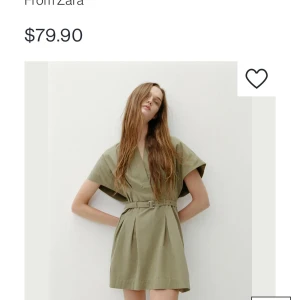 Olivgrön klänning från Zara - Snygg olivgrön klänning från Zara med korta ärmar och ett bälte i midjan för en smickrande passform. Klänningen har en v-ringad design och är perfekt för en stilren look. Den är tillverkad i ett lätt och bekvämt material.