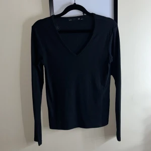 Svart ribbad tröja från 157 - Säljer en stilren svart ribbad tröja från 157. Tröjan har en v-ringad hals och långa ärmar, perfekt för en enkel och snygg look. Passar bra till både jeans och kjol. 🖤