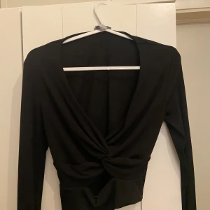Svart ribbad topp med knutdetalj - Snygg svart topp i bra skick. Den är använd ett få tal gånger och är perfekt till ett festligt tillfälle💕