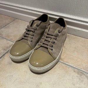 Beige/olivgröna Lanvins 39-40 - Extremt snygga lanvin med snörning och en unik glansig tådel. Skorna har en stilren design med en kombination av mocka och syntetmaterial. Perfekta för en avslappnad stil. Tyvär medföljer ej någon box, skick 8/10. Priset går självklart att diskutera!