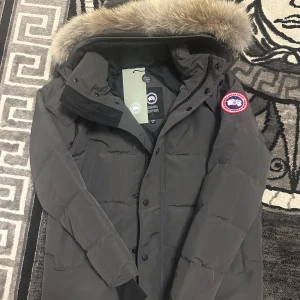 Grå parkajacka från Canada Goose - En fin Canada goose Wyndham parka grå färg storlek S aldrig använt.