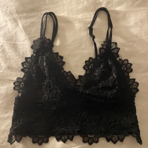 Svart spetslinne - Snyggt svart spetslinne med justerbara axelband och vacker spetsdetalj runt kanterna. Perfekt för att lägga till en touch av elegans till din outfit.