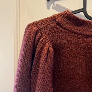 Vinröd stickad tröja från Gina Tricot - Mysig vinröd stickad tröja från Gina Tricot med långa ärmar och en bekväm passform. Perfekt för kyligare dagar med sin varma och mjuka textur. Tröjan har en enkel design som gör den lätt att matcha med olika outfits. Finns noppror som syns på nära håll men inget man riktigt tänker på. 