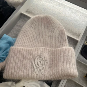 Beige stickad mössa från Carin Wester - Aldrig använd!!! Endast testad. Säljer en mysig beige stickad mössa från Carin Wester. Mössan har en uppvikt kant och ett broderat CW-märke framtill. Perfekt för kyliga dagar! 