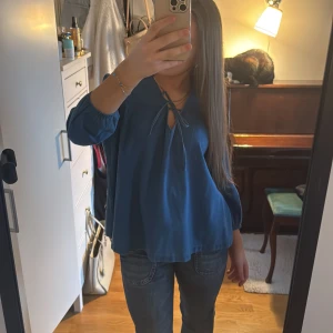 Blå blus från Esprit - Säljer en snygg blå blus från Esprit med knytning vid halsen. Blusen har långa ärmar och en luftig passform, perfekt för både vardag och speciella tillfällen. Den är tillverkad i ett mjukt och bekvämt material. 