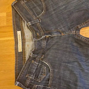 Låg midjade jeans  - Snygga låg midjade blå jeansbyxor med femficksdesign och kontrastsömmar. Byxorna har en dragkedja och knapp framtill. De är i fint skick🩷🫶