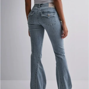 Blå jeans från True Religion - Blåa true religion jeans, low waist. Har endast använt en gång och säljer då dom inte kommer till användning! Är ca 165cm och de är långa på mig. De är i storlek W23, alltså XXS/XS typ. Jätte fina och jätte sköna! Inga defekter alls, ser helt helt nya ut. 