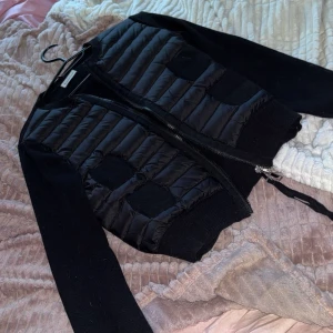 Svart moncler cardigan  - Svart moncler cardigan köpt 2024. Använd utomhus 2-3 gånger och har absolut inga defekter överhuvudtaget. Den är super fin och ser ut att komma direkt från butik fortfarande!❣️